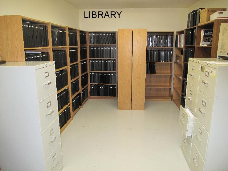 A library with many shelves of books and some filing cabinets.